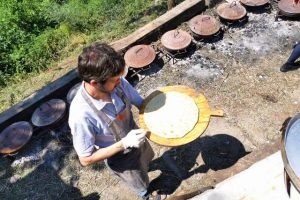 Preparazione della pizza che sarà cotta con i tradizionali 'testi' di ghisa.